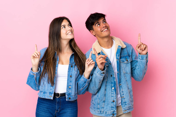 Молодая пара на изолированном розовом фоне указывая указательным пальцем отличная идея - Фото, изображение