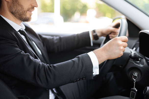 Unrecognizable businessman holding hands on steering wheel, driving car - 写真・画像