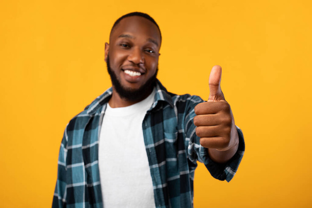 Positiver Afroamerikaner gestikuliert Daumen hoch, Studioaufnahme - Foto, Bild