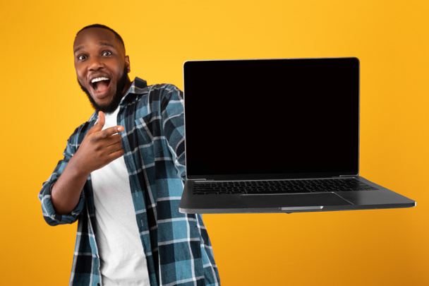 Emocional afro-americano cara mostrando tela de laptop sobre fundo amarelo - Foto, Imagem