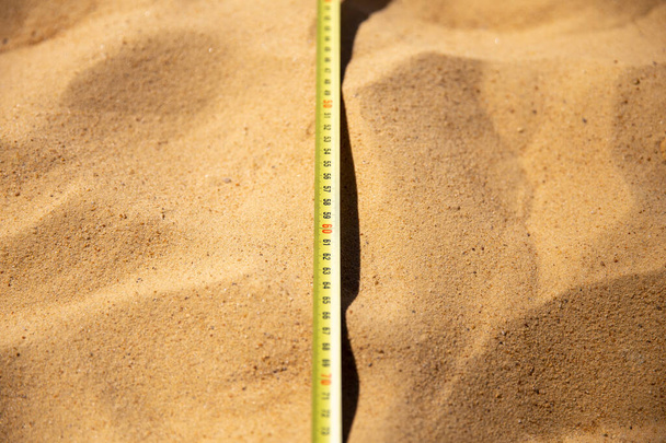 Міра стрічки лежить на піску, змагання з стрибків у довжину. Вимірювання довжини, розміри спортивного поля, майданчик для гри
 - Фото, зображення