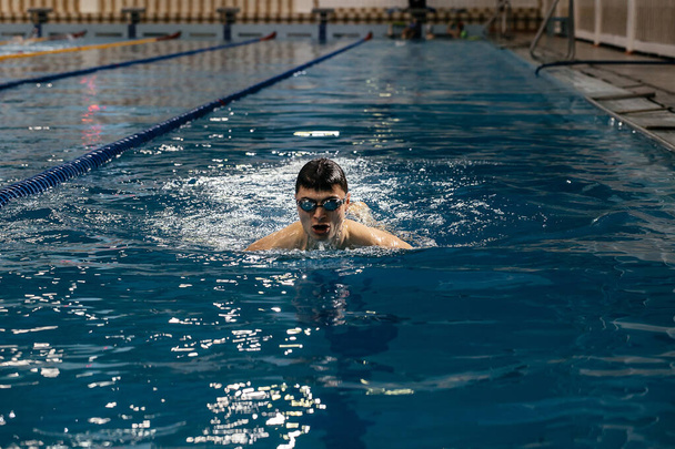 Swimming sports athlete swimmer swims in the pool, preparing for the race. Professional mens water sports for adults, engaged in cardio training in the water in the indoor pool. Panoramic banner. - Fotografie, Obrázek