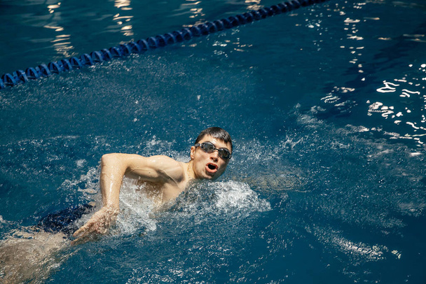 Τρίαθλο αθλητής προπονείται για να κολυμπήσει στην πισίνα. Λευκός άντρας κολυμπά σε μπλε πανόραμα πανόραμα. Αθλητισμός και γυμναστική ασκήσεις καρδιο. - Φωτογραφία, εικόνα