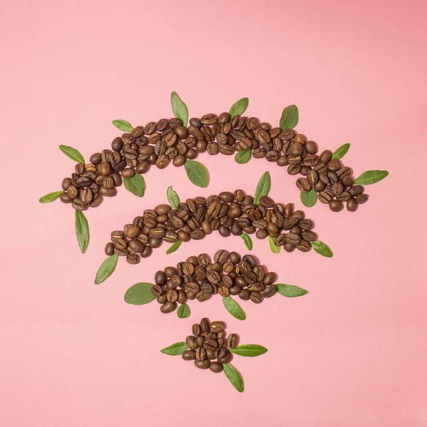 Wi-Fi sign made of coffee beans and fresh plant leaves. Creative flat lay background. - Фото, зображення