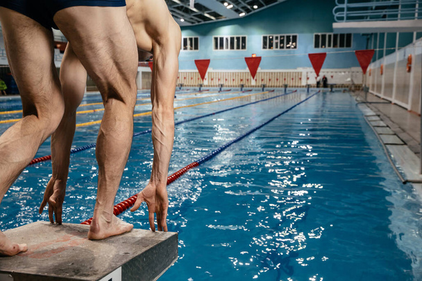 nageur humain, un jeune athlète nage dans un style libre sur l'eau bleu azur dans la piscine. vue du bas - Photo, image