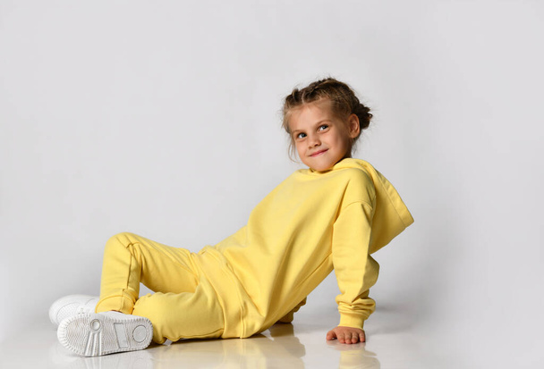 Stylish little girl sitting on a white background looking at you. - Фото, изображение
