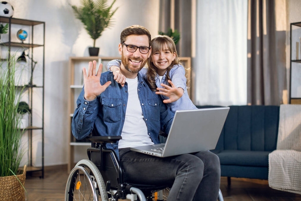 Disabled father and daughter smiling and waving on camera - Φωτογραφία, εικόνα