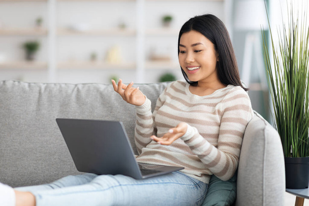 feliz jovem sorrindo asiático senhora fazendo vídeo chamada no laptop em casa - Foto, Imagem