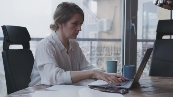 Νεαρή γυναίκα εργάζεται για ένα φορητό υπολογιστή στο γραφείο κάνει την επαγγελματική αλληλογραφία. - Πλάνα, βίντεο