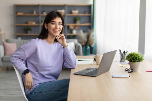 Πορτρέτο της χαμογελαστή νεαρή γυναίκα κάθεται στο γραφείο - Φωτογραφία, εικόνα