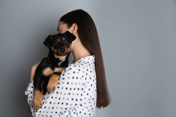 Young woman with cute puppy on light grey background. Space for text - Foto, Bild