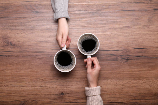 Women with cups of coffee at wooden table, top view - Photo, Image