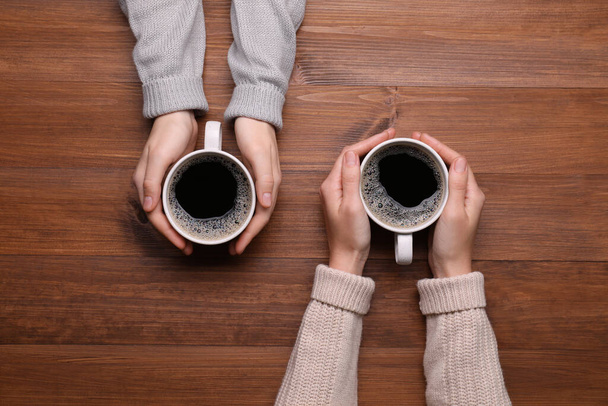 Women with cups of coffee at wooden table, top view - Photo, image