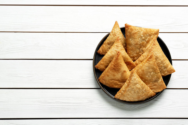 Fresh delicious crispy samosas on white wooden table, top view. Space for text - Φωτογραφία, εικόνα