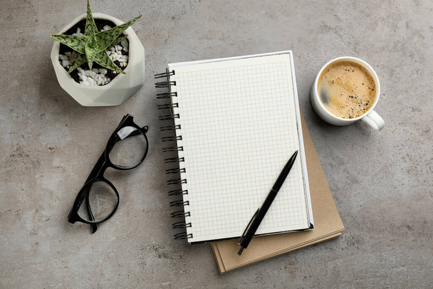Notebooks, cup of aromatic coffee, glasses and plant on grey table, flat lay - Fotoğraf, Görsel
