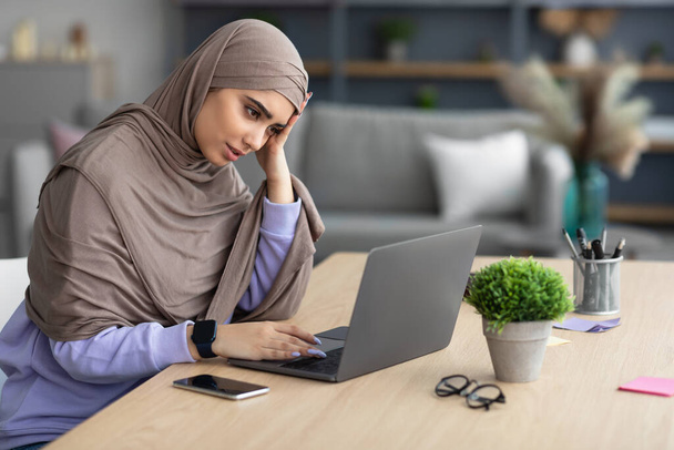 疲れているイスラム教徒の女性は、机に座って、コンピュータを使用して - 写真・画像