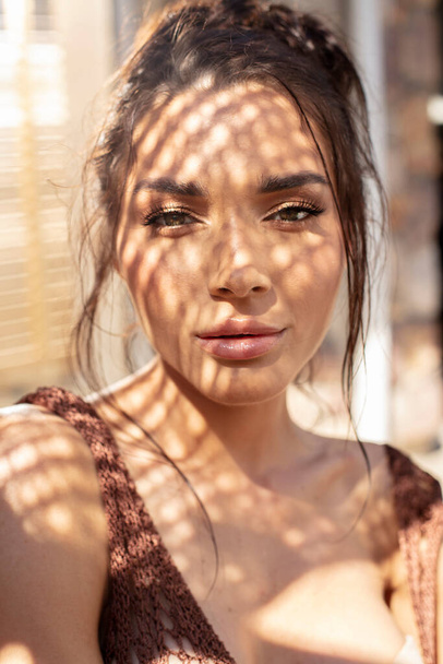 Beauty portrait of brunette woman with beautiful eyes looking at camera, posing at sunny summer day. Shadows on models face.  - Photo, Image