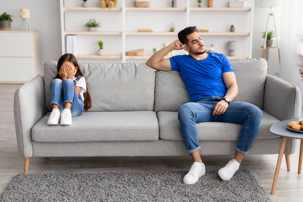 Pai sentado separado no sofá com a filha chorando ofendido - Foto, Imagem