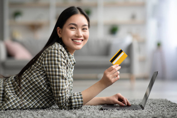Onnellinen nainen käyttää kannettavaa tietokonetta ja luottokorttia kotona - Valokuva, kuva