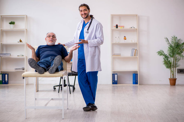 Vecchio paziente maschio visita giovane medico chiropratico maschile - Foto, immagini