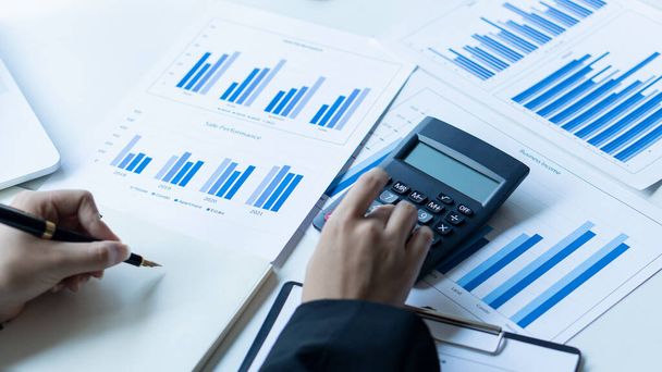 Biznesmeni analizują statystyki finansowe za pomocą wykresów, wykresów i kalkulatorów z laptopem i mówią o wzroście firmy A w garniturze biurowym. - Zdjęcie, obraz