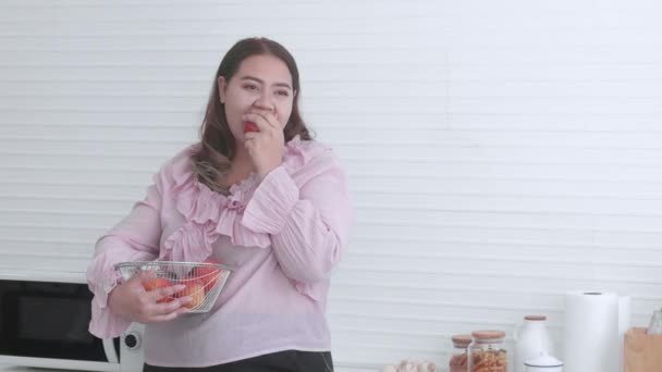 Fiatal ázsiai nő kövér álló eszik alma otthon a konyhában, gyümölcs az egészséges, fogyás és fogyás, nő túlsúlyos és táplálkozás egészségügyi ellátás, plusz méret, életmód koncepció. - Felvétel, videó