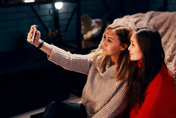 Deux jolies filles en chandails tricotés prennent selfies. - Photo, image