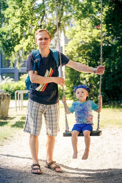 Πατέρας σπρώχνει γιος (4-5) σε κούνια στο πάρκο - Φωτογραφία, εικόνα