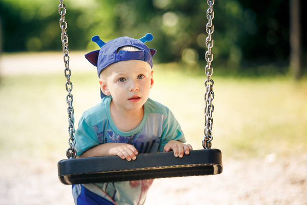 Porträt eines kleinen Jungen, der im Park mit Schaukel spielt - Foto, Bild