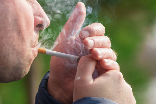Обрізаний крупним планом чоловік запалює сигарету на відкритому повітрі
. - Фото, зображення