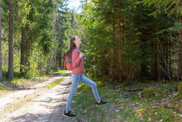 Pretty one teen young tourist girl relaxing on forests road.Teenage with backpack on green forest summer or spring. - Photo, Image