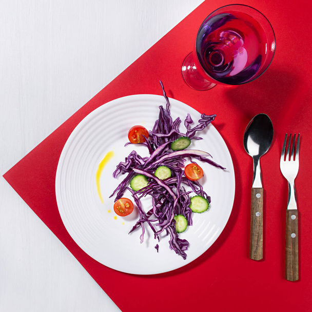 Wellness food - fresh salad of tomato, cucumber, red cabbage on white plate in hard light with shadow with drink on red background, white board, square. - Photo, image