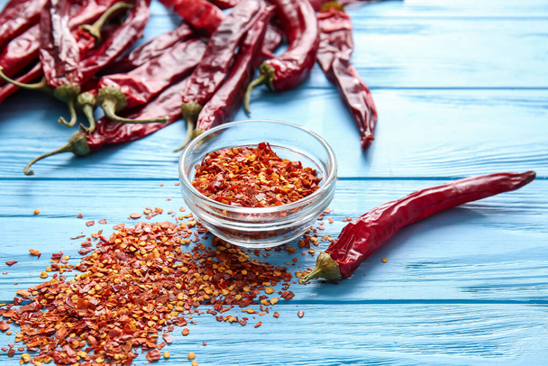 Bowl with ground chili pepper on color wooden background - Foto, immagini
