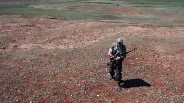負傷した疲れた狙撃兵が熱い砂漠を歩いている。極限状態における武力紛争と生存の概念. - 映像、動画