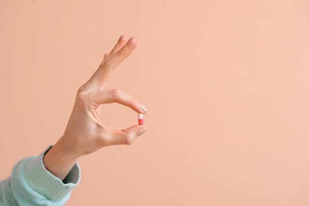 Woman with pill showing OK on color background - Foto, afbeelding