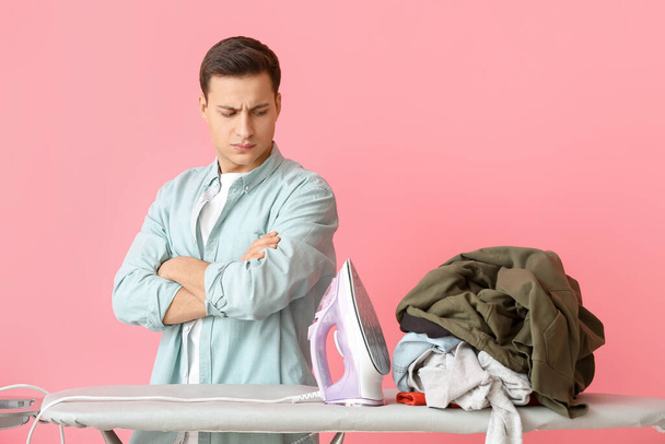 Handsome young man with laundry on color background - Photo, Image