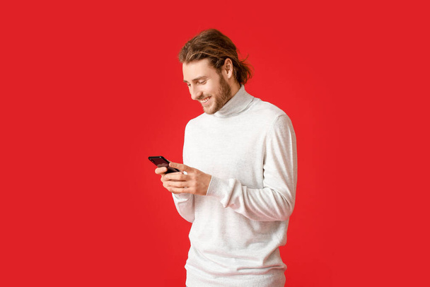 Young man using mobile phone on color background - Photo, Image