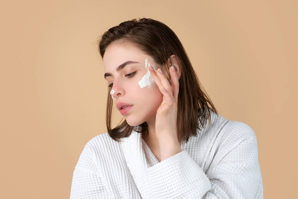 Woman beauty face, portrait of beautiful female model applying moisturizer cream on her pretty face. Skincare and healthy skin, spa facial treatment concept. - Fotó, kép