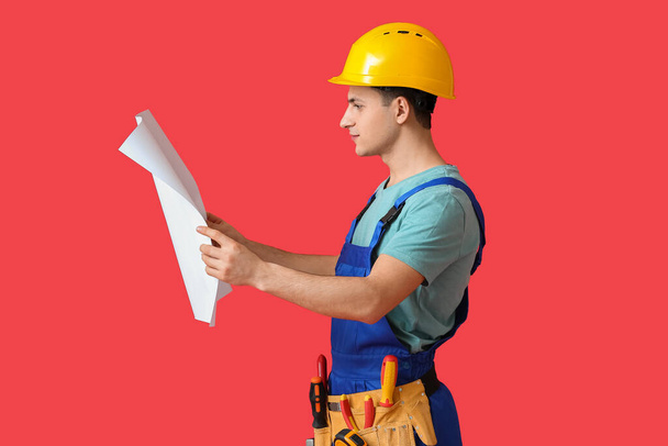 Young electrician with house plan on color background - Foto, Imagem