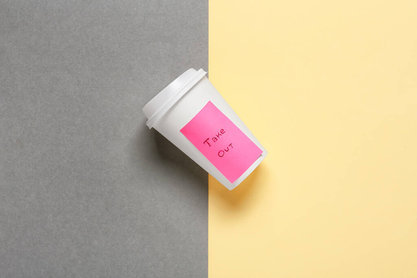 Blank paper cup with text TAKE OUT on color background - Фото, изображение