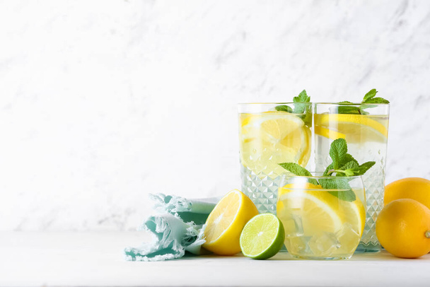 Glasses of tasty cold lemonade on light background - Fotó, kép