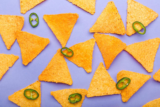 Lekkere nacho 's met chili peper op kleur achtergrond - Foto, afbeelding