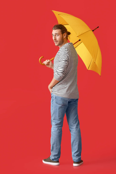 Όμορφος νεαρός άνδρας με ομπρέλα στο φόντο χρώμα - Φωτογραφία, εικόνα