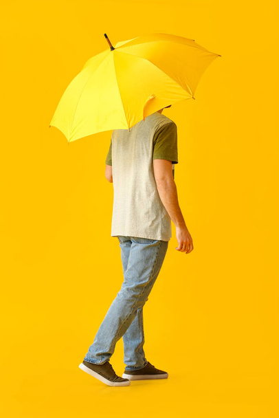 Handsome young man with umbrella on color background - Фото, изображение