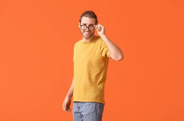 Νεαρός άνδρας που φοράει γυαλιά στο φόντο του χρώματος - Φωτογραφία, εικόνα