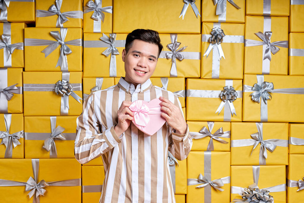 Best prices for gifts. Asian Man in studio room full of gifts, many holiday packages. Holidays filled with fun. - Photo, image