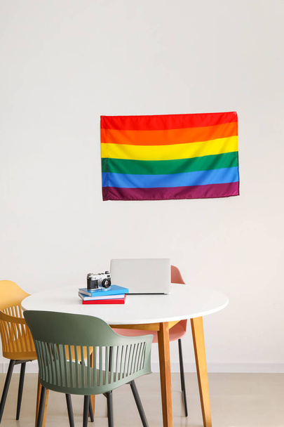Moderner Arbeitsplatz mit LGBT-Fahne an der Wand im Raum - Foto, Bild