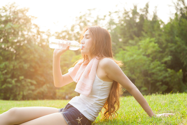 Woman sitting tired and drinking water after exercise. - 写真・画像