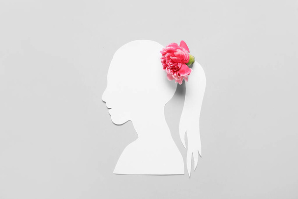 Paper female figure and beautiful carnation flower on color background - Photo, Image