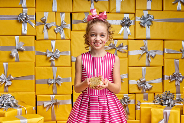 Little caucasian girl holding cake in hands, smiling, enjoying birthday - Foto, Bild